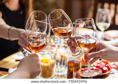 Hand holding glasses with rose wine over a table rich with Balkan and Moldovan cuisine dishes Royalty-Free Stock Photo #730692496