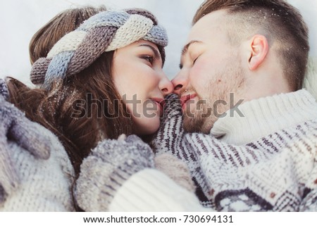 People, season, love and leisure concept - happy couple hugging and laughing outdoors in winter. Couple embracing in snowy winter park
