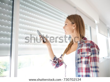 Woman using smartphone to control electric shutter Royalty-Free Stock Photo #730702534