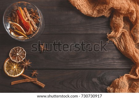 Ingredients for mulled wine: Dried citrus, orange, lemon, and spices, anise, cinnamon, on a wooden background with an orange cloth. Christmas mood, homely atmosphere. Space for text