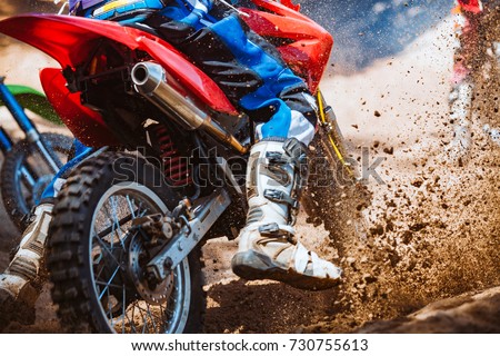 Close-up part of mountain bikes race in dirt track with flying debris during an acceleration in sunshine day time. Concept of focus between an accelerate in action sport Royalty-Free Stock Photo #730755613