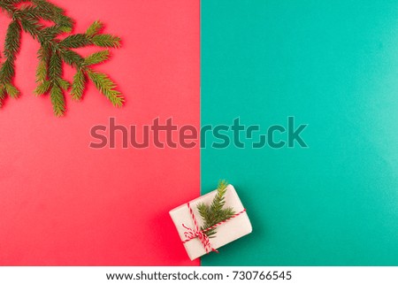 Christmas composition. Fir tree branche and gift box on red and green background.