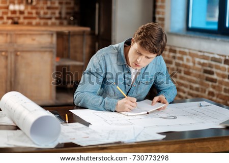 Young engineer making notes regarding his project