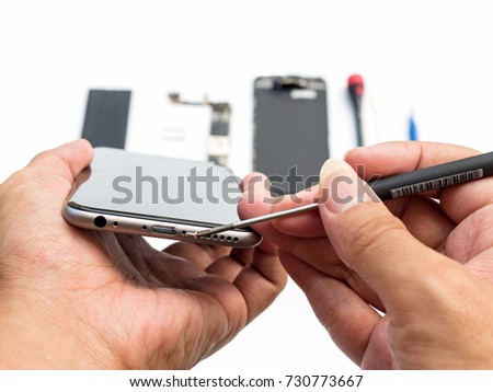 Close-up of technician being unlock screw with screwdriver on blurred smartphone component background
