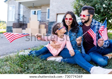 family with american flags and sunglasses sitting in garden of new house