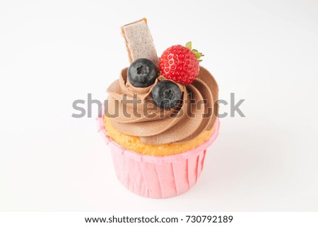 Pink cupcake with chocolate whipped cream decorated with strawberry, blueberry, granola bar on white background. Picture for a menu or a confectionery catalog.