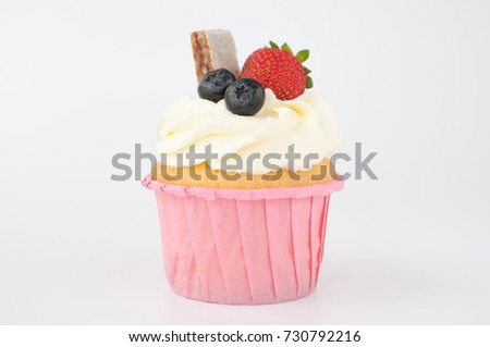 Pink cupcake with white whipped cream decorated with strawberry, blueberry, granola bar on white background. Picture for a menu or a confectionery catalog.