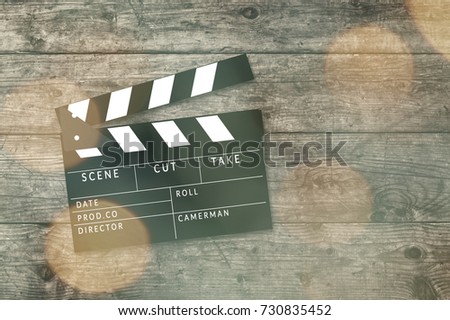 Movie clapper board on wooden background with bokeh lights.