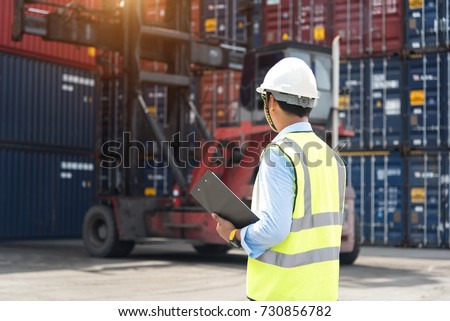 Foreman control loading Containers box from Cargo freight ship in Warehouse shipping transportation concept. Royalty-Free Stock Photo #730856782