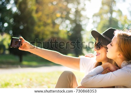 Two girlfriends taking selfie in the park