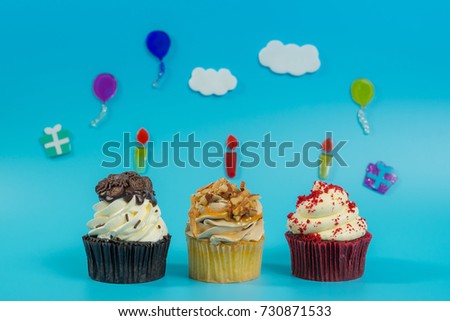 Close up front view of birthday cupcakes decorated with cloud and colorful balloon in blue background
