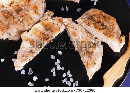 Steaks with grill on a black plate with a wooden fork, large salt, spices and peanuts on a dark blue background in retro style