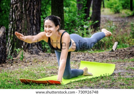 A young girl does exercise on balance while practicing Pilates in nature.