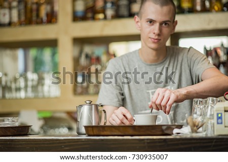 Barista bartender stirring coffee in a small espresso cup in a coffee shop