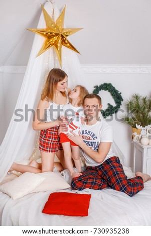 Family with a girl in the studio for the new year. Parents with a little daughter in a Christmas photo session. Studio shooting before the holidays.