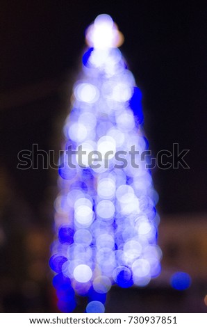 Blurred silhouette of a Christmas tree with a star with blue blurred lights with bokeh effects at night