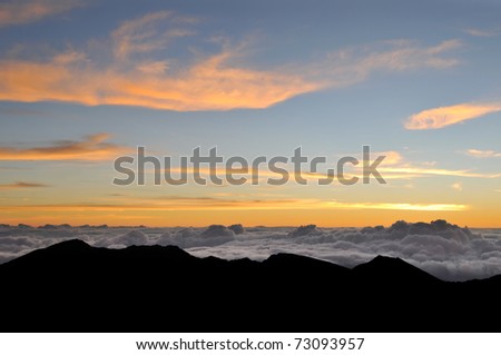 Dark heavenly clouds in the sky. Beautiful orange and blue color with the silhouette of a mountain on the bottom of the frame.