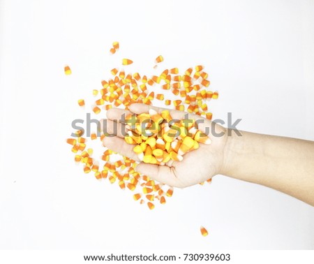 Female left hand holding candy corn on a white background