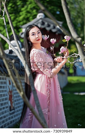 Sweet beautiful girl in pink dress, near blooming magnolia 