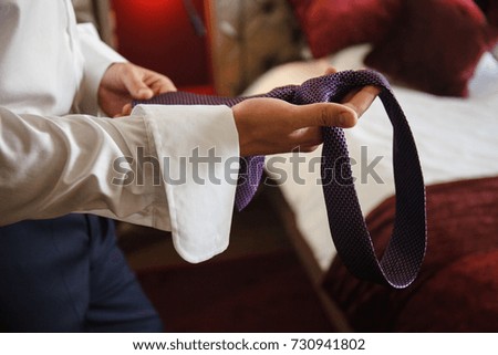 elegant man ties up a tie
