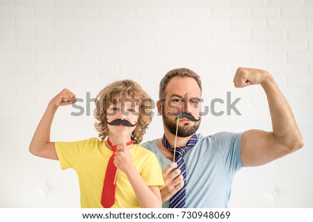Funny man and kid with fake mustache. Happy family playing in home. Movember concept Royalty-Free Stock Photo #730948069