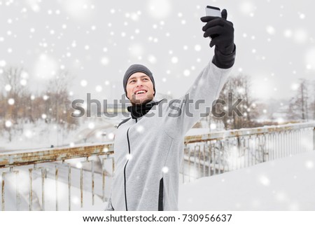 fitness, sport, people, exercising and healthy lifestyle concept - young man taking selfie with smartphone in winter 