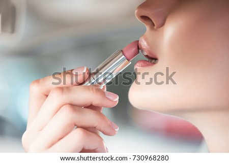 Cropped shot of a young woman applying a light pink lipstick
