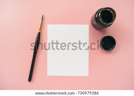 Styled artist workspace on a pink background. White paper mock up with space for text