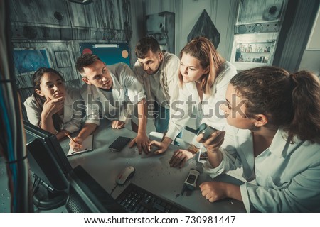 Five positive italian adults solving conundrums together in quest room in view as abandoned lab Royalty-Free Stock Photo #730981447