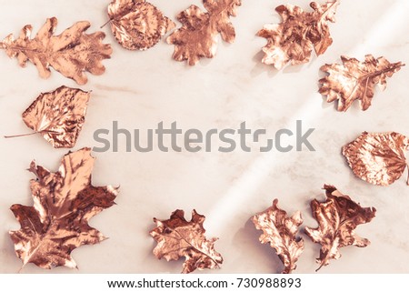 Frame made of fall rose gold colored leaves, creative flatlay on white marble background. Copy space for text