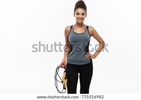 Sport, training, lifestyle and Fitness concept - portrait of beautiful happy African American woman exercising with jumping rope. Isolated on white studio background.