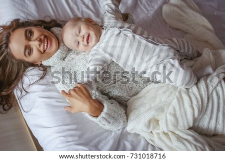 Little cute baby and beautiful mother in bed