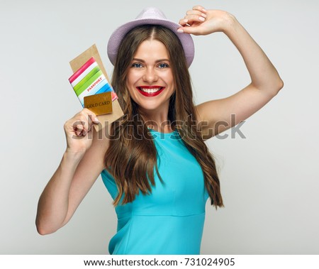 Smiling woman wearing blue dress holding credit cart and passport.
