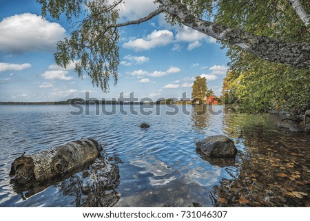 Picture of red wooden scandinavian style house at the lake during autumn.