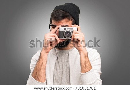 Hipster man holding a camera on grey background