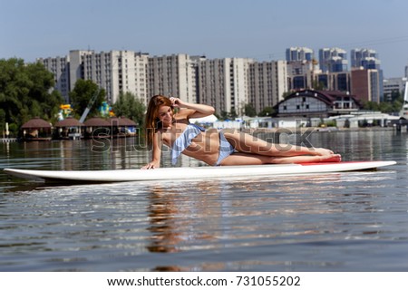 a beautiful smiling girl with perfect body practicing paddle on a beautiful sunny day 