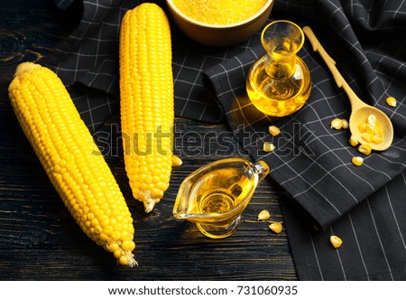 Composition with corn oil, cobs and kernels on wooden background