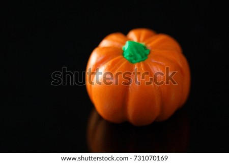 little polymer clay pumpkin on dark reflective background