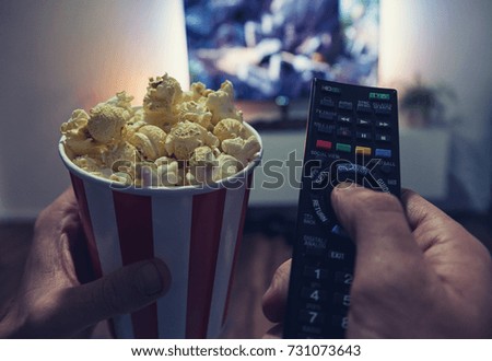 young man Watching a Movie in his living room with popcorn and remote control, Point of view shot Royalty-Free Stock Photo #731073643