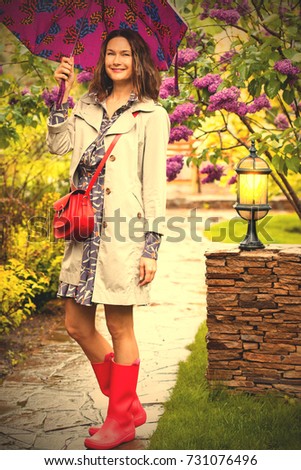 beautiful smiling European woman dressed up in a raincoat with an umbrella in the park. style and fashion. instagram image filter retro style