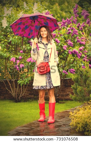 beautiful European woman dressed up in a raincoat with an umbrella in the park. style and fashion. instagram image filter retro style