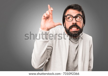 Hipster man with his fingers crossing on grey background