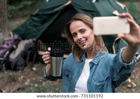 Happy female tourist making selfie in forest