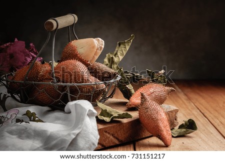 still life picture of salacca fruit on wood decorated with dried leaves and flower, there is copy space for any text