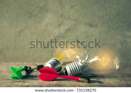 Shining light bulbs with darts in still life photography shooting, competition idea target concept   