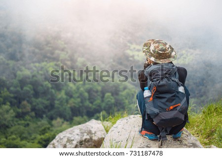 rear of man sitting on rock at mountain looking view with mist and cloud at Doi Luang Tak, Tak Province, Thailand. subject is blurred.