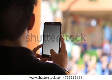 Man holding mobile phone for take picture with background.