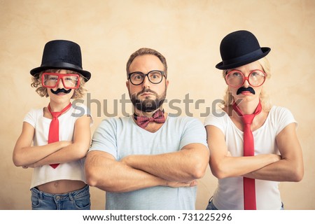 Funny man, woman and kid with fake mustache. Happy family playing in home. Movember concept Royalty-Free Stock Photo #731225296