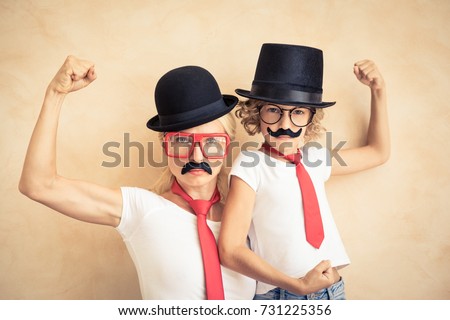 Funny woman and kid with fake mustache. Happy family playing in home. Movember concept Royalty-Free Stock Photo #731225356