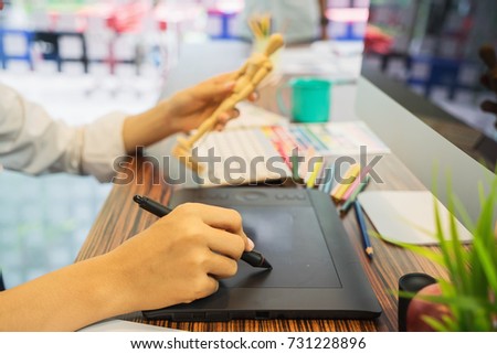 Young graphic designer working on modern desktop computer while using graphic tablet at desk in the office.